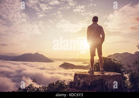 Man on a summit above the clouds Stock Photo