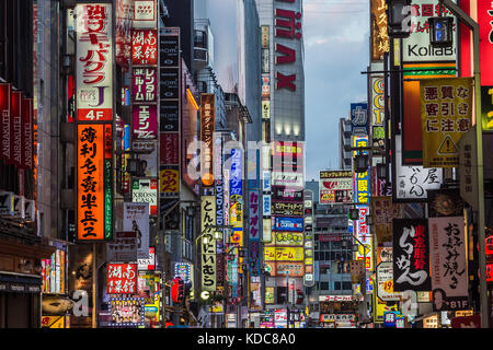 Neon lights and shops along street in Ginza district at dusk in Tokyo