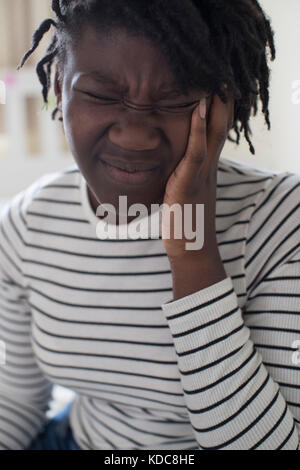 Teenage Girl Suffering With Headache In Bedroom Stock Photo