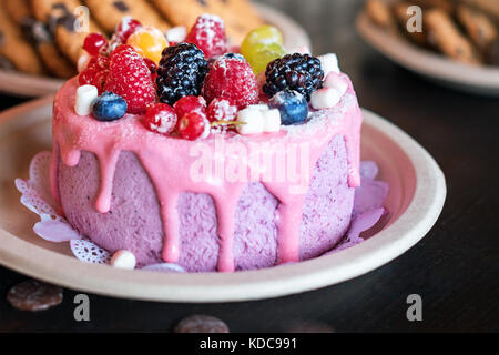 Sweet cheese cake with fresh berries and yoghurt cream. Delicious raspberry cake with fresh strawberries, raspberries, blueberry, currants and blackberry fruits on rustic wooden background. Stock Photo