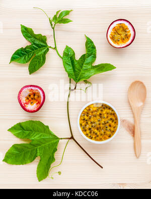 Fresh passion fruits set up on wooden background. Juicy passion fruits with green leaves  and Passion fruit vine flat lay . Stock Photo