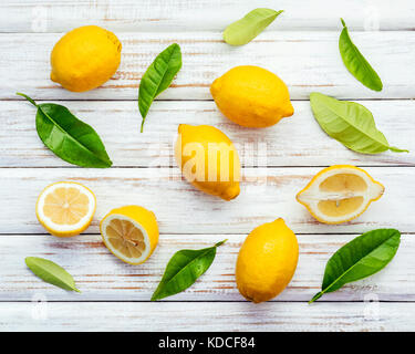 Fresh lemons and  lemons leaves on rustic wooden background. Fresh lemons and lemon slice on wooden table with flat lay.  Fresh citrus fruit backgroun Stock Photo