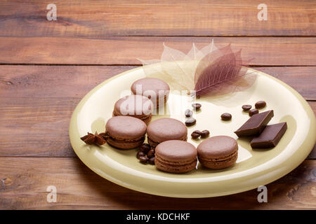 French macaroons with coffee beans and chocolate on a plate over wooden background Stock Photo