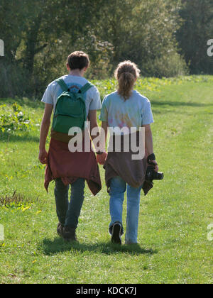 Young adult couple walking and holding hands, UK Stock Photo