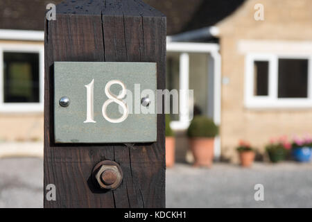 The number 18 on a slate plaque attached to a gate post at the entrance to a UK home. Signifying it's address. Stock Photo