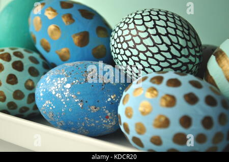 Decorated Easter eggs with gold polka dots on mint teal aqua blue background. Styled stock image with copy space. Easter and spring theme.