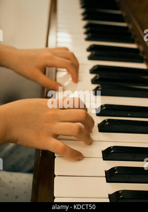 Close up of young girl playing piano at home Stock Photo