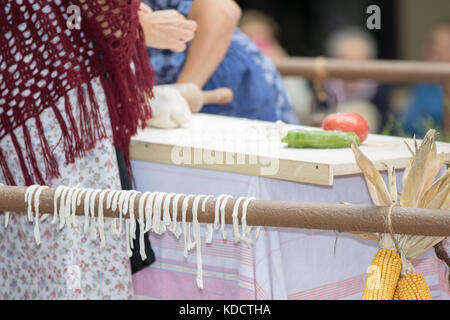 Asti, Italy - September 10, 2017: women dressed in vintage dresses knead and spread pasta Stock Photo