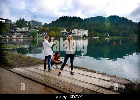 Young women using smart phones beside Lake Bled, Bled, Slovenia. Stock Photo