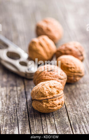 Tasty dried walnuts and nutcracker on old wooden table. Stock Photo