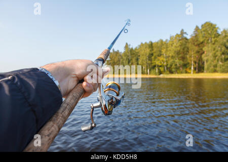 Fishing on a lake. Fishing rod with a reel in hand. Vew of the shore. Stock Photo