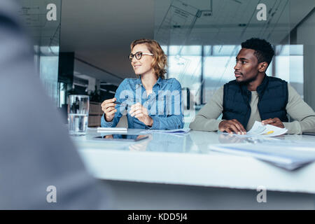 Female executive listening to her colleague during meeting. Creative professionals discussing business in board room. Stock Photo