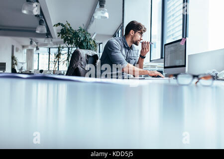 Male executive working on computer and talking on mobile phone. businessman working in office with phone. Stock Photo