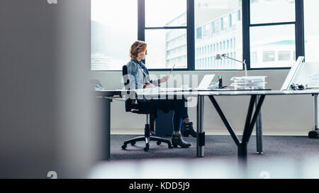 Young businesswoman with digital tablet working at her desk. Female designer working in office. Stock Photo