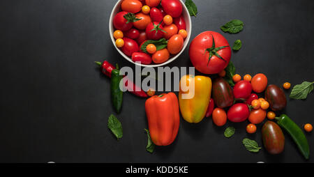 Tomatoes, chilies, bell peppers and dill leaves on table. Red and yellow bell peppers placed along side tomatoes, mint, chillies and dill leaves. Stock Photo