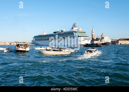 Congestion in the Venetian lagoon as the the Royal Caribbean Cruise ship, 'Rhapsody of the Seas' makes its way past San Giorgio Maggiore. Venice, Ital Stock Photo