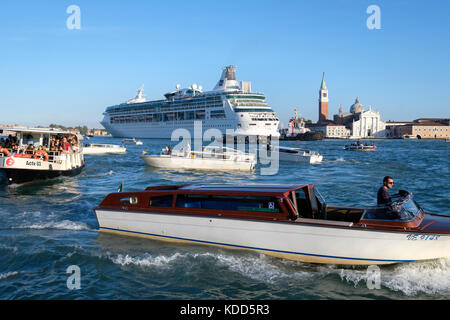 Congestion in the Venetian lagoon as the the Royal Caribbean Cruise ship, 'Rhapsody of the Seas' makes its way past San Giorgio Maggiore. Venice, Ital Stock Photo