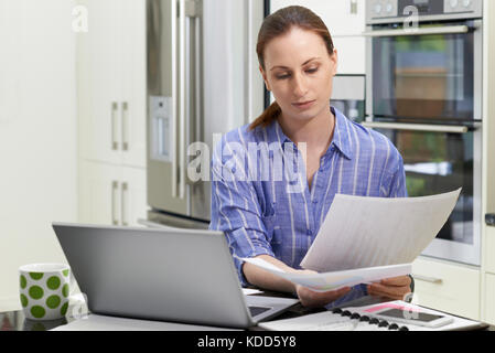 Female Freelance Worker Using Laptop In Kitchen At Home Stock Photo