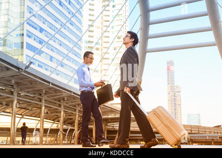 Businessman pulling suitcase walking in modern city,abstract business concept. Stock Photo