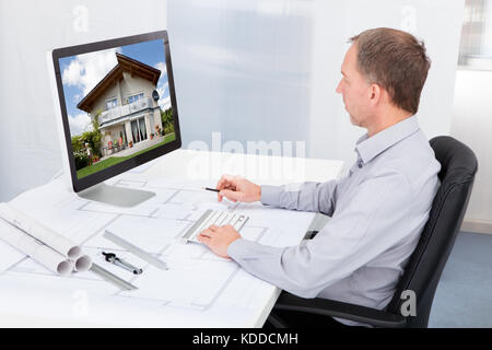 Portrait Of Mature Architect Using Computer At Office Desk Stock Photo