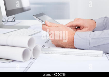 Close-up Of Architect Using Digital Tablet Over Blue Print Stock Photo