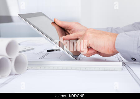 Close-up Of Architect Using Digital Tablet Over Blue Print Stock Photo