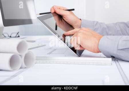 Close-up Of Architect Using Digital Tablet Over Blue Print Stock Photo