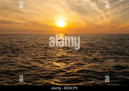 A couple of small boats can be seen out on Cardigan Bay at sunset Stock Photo