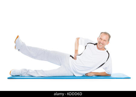 Portrait Of Mature Man Stretching Leg Lying On Exercise Mat Stock Photo