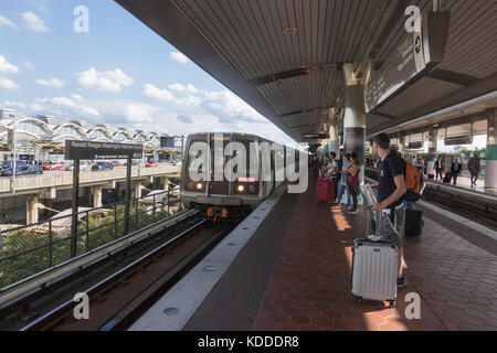 Metro station outside Ronald Regan Washington National Airport, travelers on platform, DC.  Terminal in background. Stock Photo