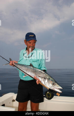 A fisherman with a kingfish or king mackerel caught while fly fishing offshore from Freeport, Texas Stock Photo