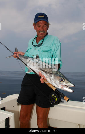 A fisherman with a kingfish or king mackerel caught while fly fishing offshore from Freeport, Texas Stock Photo