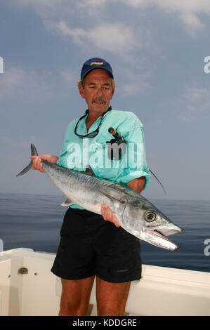 A fisherman with a kingfish or king mackerel caught while fly fishing offshore from Freeport, Texas Stock Photo