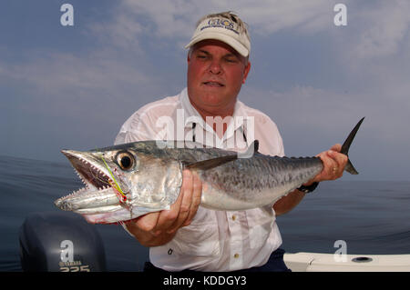 A fisherman with a kingfish or king mackerel caught while fly fishing offshore from Freeport, Texas Stock Photo