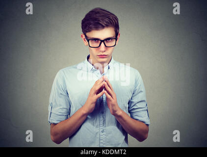 Sly, scheming man trying to plot something screw someone isolated on gray background. Stock Photo