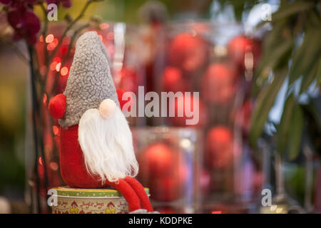 Christmas soft toy Santa Claus on a box with a gift on a background of red balls Stock Photo