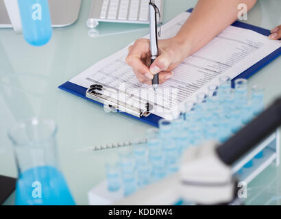 Close-up Of Female Scientist Writing On Notepad Stock Photo