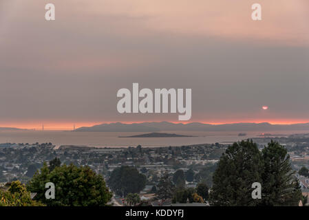 San Francisco, USA. 12th Oct, 2017. Looking west across San Francisco Bay from the East Bay hills with Golden Gate Bridge to left as the sun sets through wildfire smoke over the Marin Headlands, south of the Sonoma and Napa wildfires. Air quality on this day was rated as bad in San Francisco as in Beijing China. 12th October, 2017. Credit: Shelly Rivoli/Alamy Live News Stock Photo