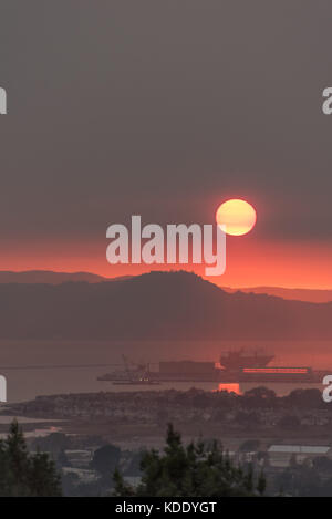 San Francisco, USA. 12th Oct, 2017. Looking west across San Francisco Bay looking over Point Richmond as the sun sets through wildfire smoke over the Marin Headlands, south of the Sonoma and Napa wildfires. Air quality on this day was rated as bad in San Francisco as in Beijing China. 12th October, 2017. Credit: Shelly Rivoli/Alamy Live News Stock Photo