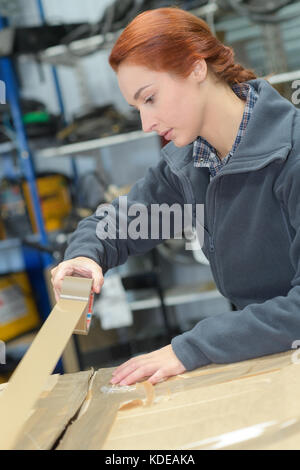 close-up of female sealing cardboard box with adhesive tape Stock Photo