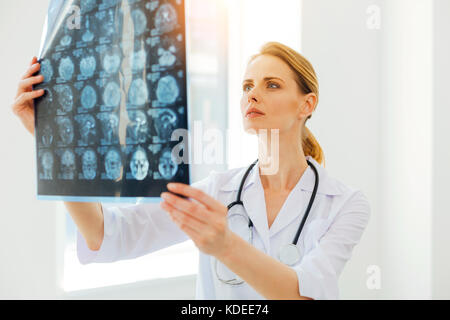 Serious female radiologist examining MRI scan image Stock Photo