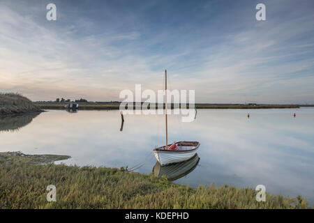 Clouds and a small boat reflected in the still water at Walton & Frinton Yacht Club, Walton on the Naze, Essex, UK. Stock Photo