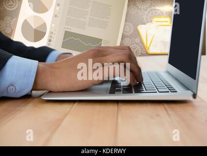 Digital composite of Business hand with laptop at desk with diagrams and charts Stock Photo
