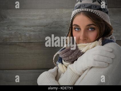 Digital composite of Woman against wood with warm hat and scarf and gloves Stock Photo