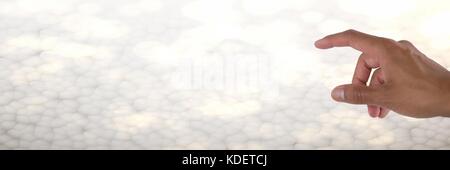 Digital composite of Hand interacting and touching air with bright background Stock Photo
