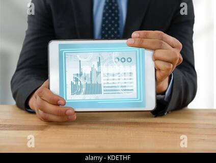 Digital composite of Businessman with tablet at desk with diagrams and charts Stock Photo
