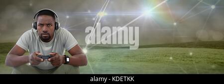 Digital composite of man playing with computer game controller with light connections on green hills background Stock Photo