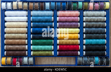 Colored sewing threads on spools arranged in a box. Stock Photo