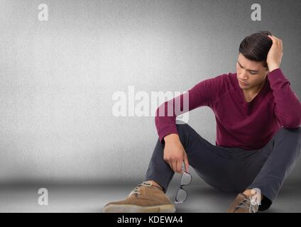 Digital composite of Man depressed and upset witting on floor with glasses and darkness Stock Photo