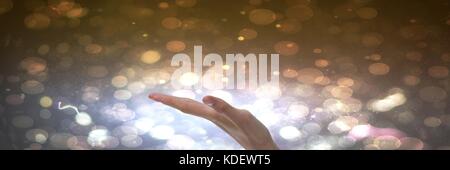 Digital composite of Hand interacting and open with bright sparkling lights background Stock Photo